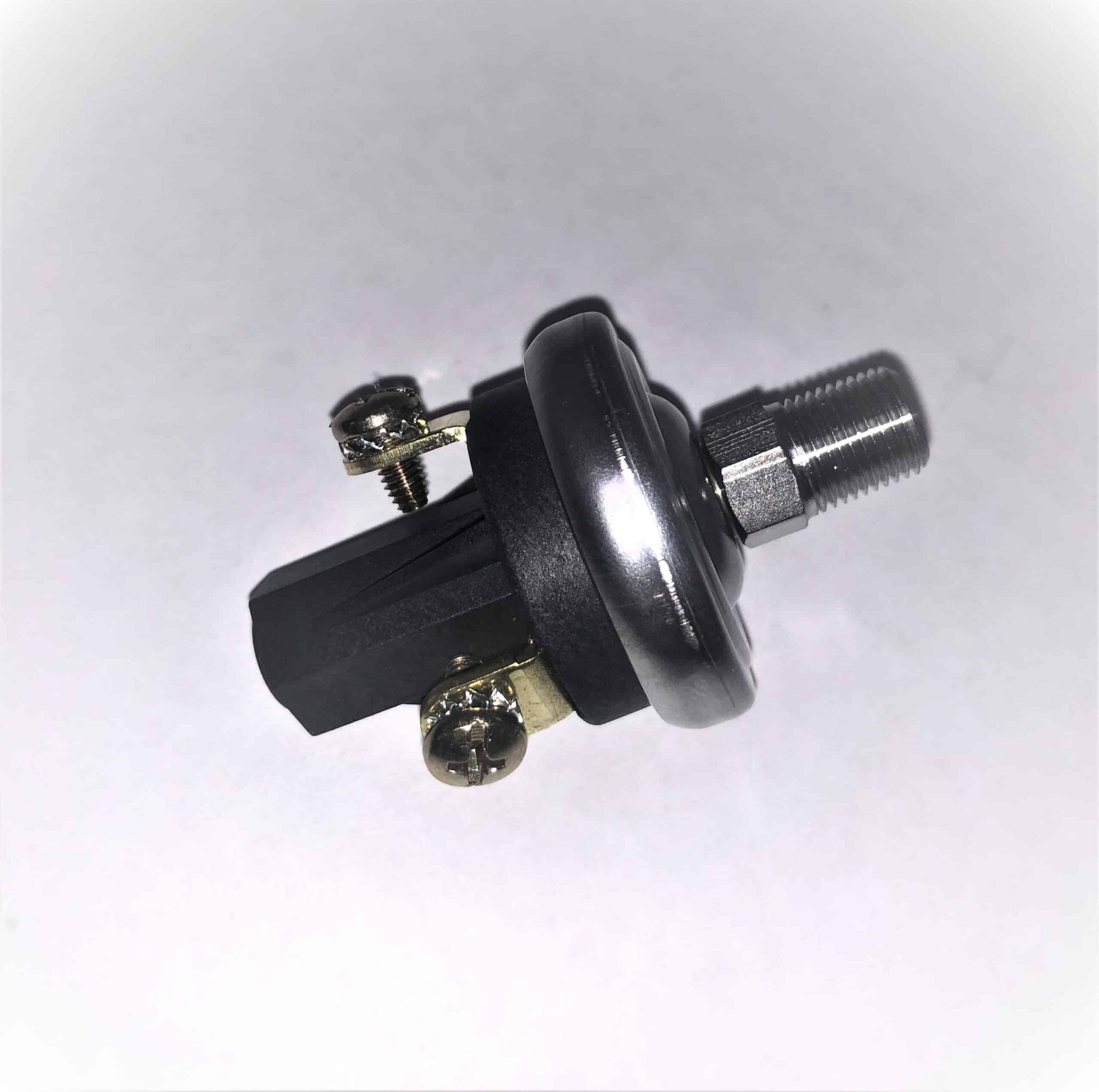 Close-up of a mechanical part with a metal threaded end, black plastic body, and two screws securing brass terminals, photographed on a white background.