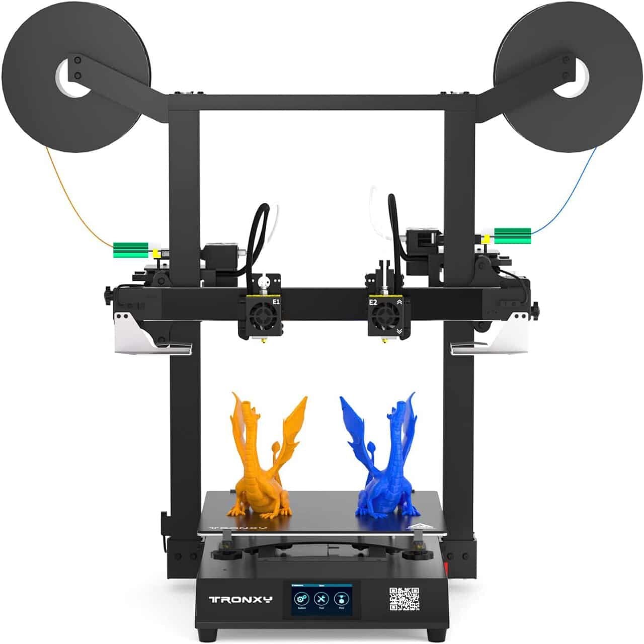 A dual-extruder 3D printer prints two dragon models, one orange and one blue, with two spools of filament mounted on top and a digital control panel at the front labeled TRONXY.
