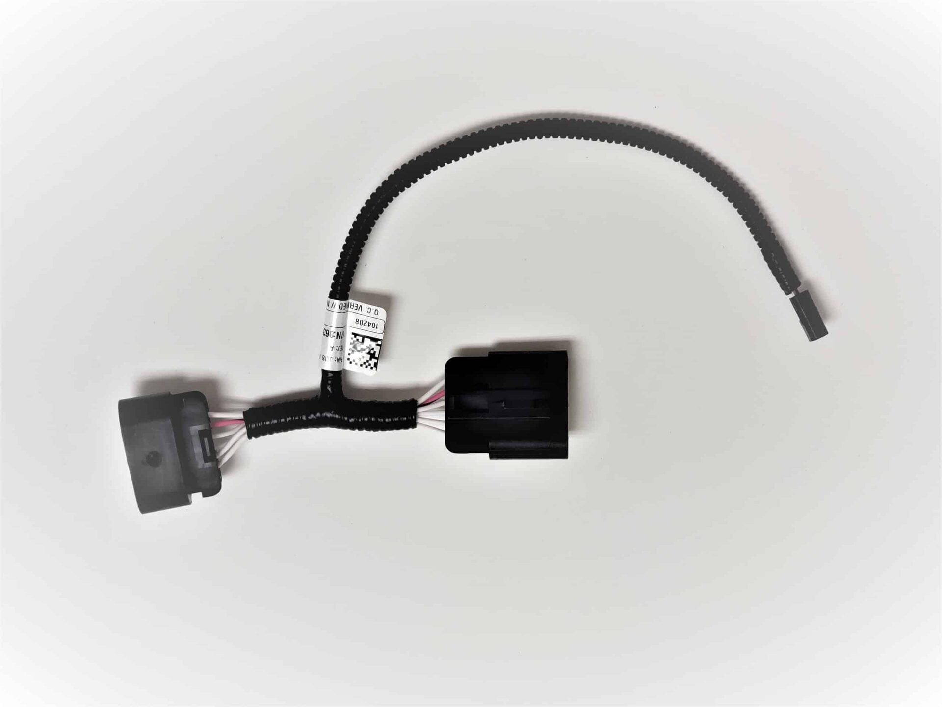 A black automotive wiring harness with connectors and a protective sleeve, featuring a white label with barcodes and numbers, displayed on a white background.