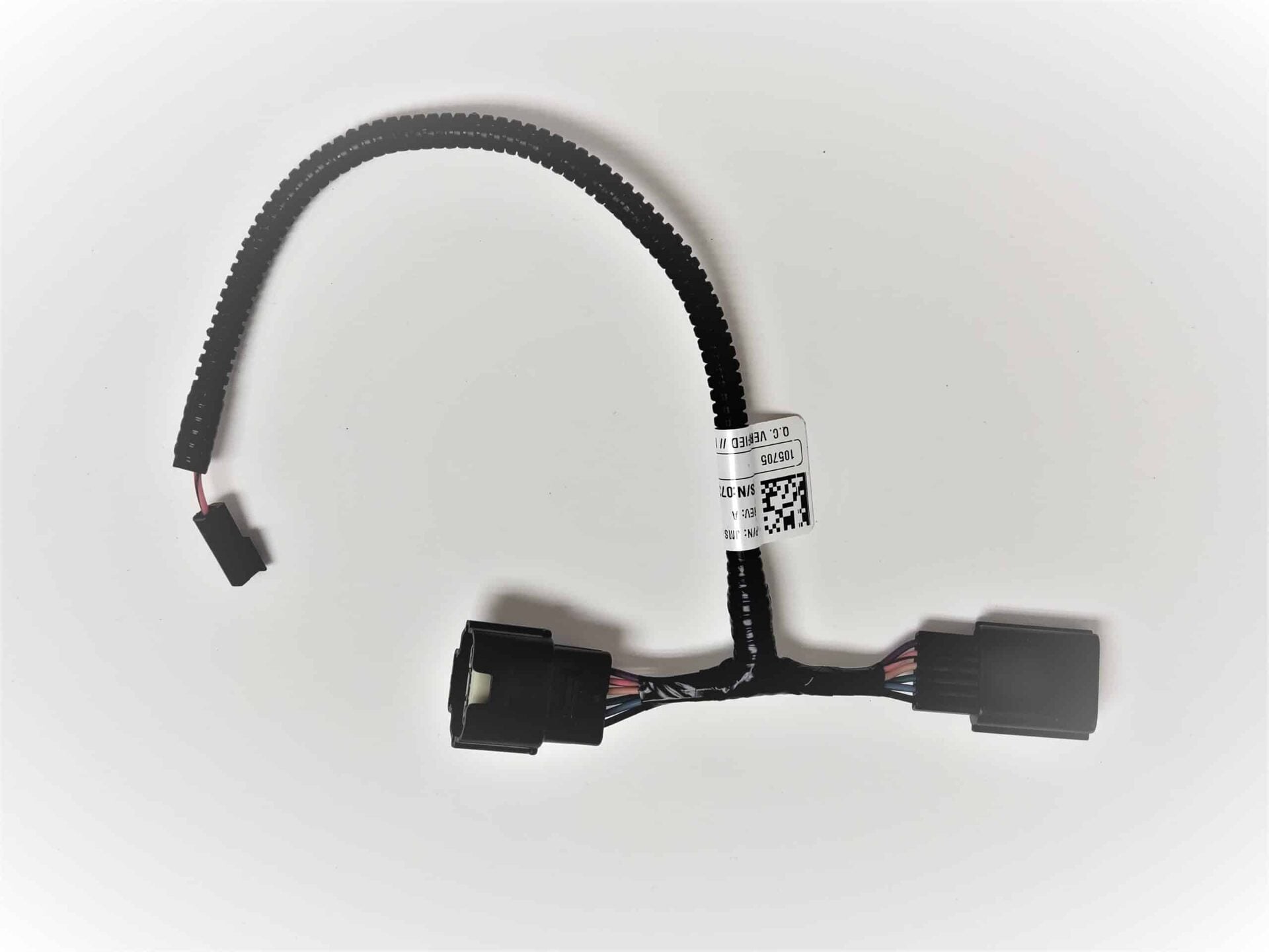 A black electrical wiring harness with connectors at each end and a white barcode label attached to one side, displayed on a plain white background.