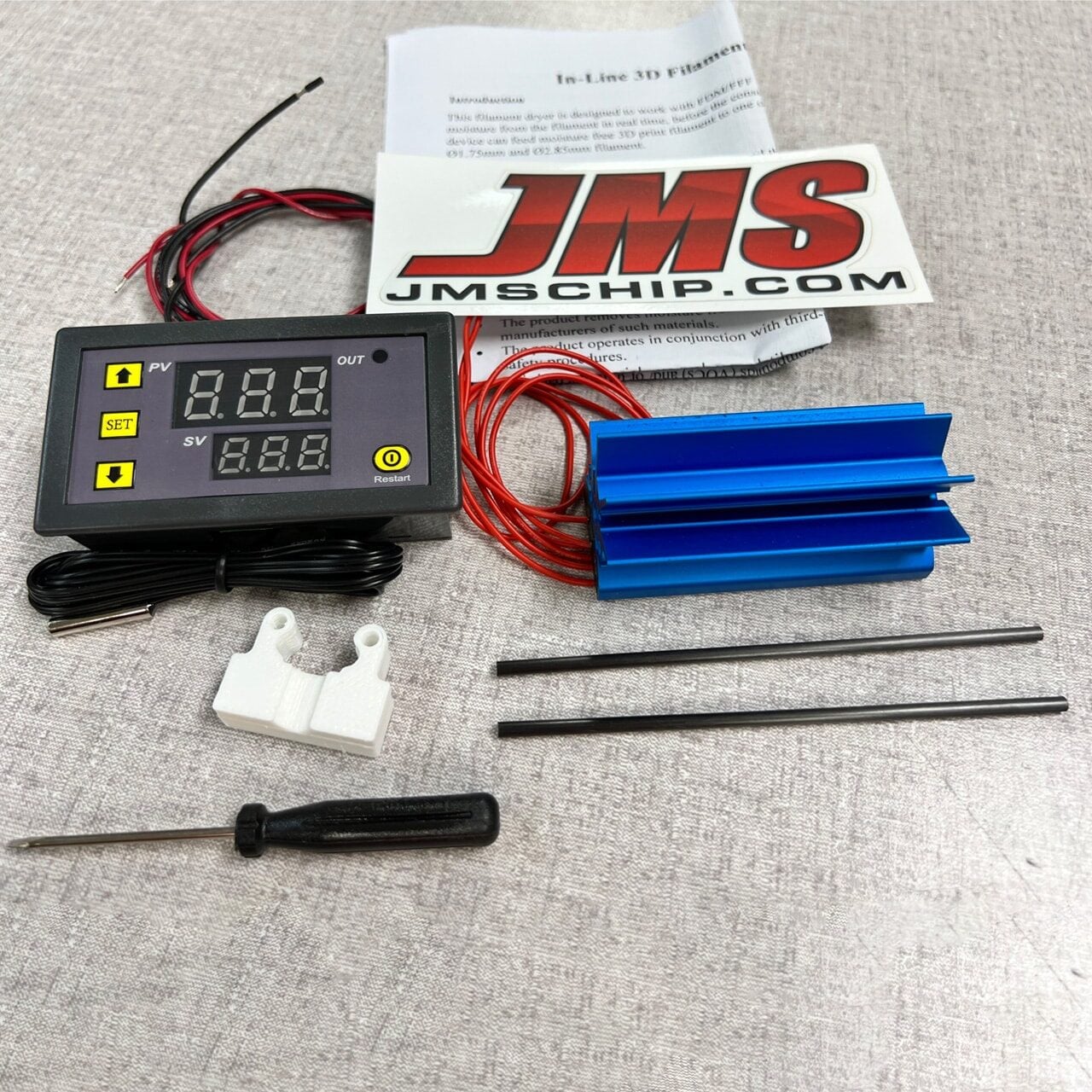 A digital control panel with wires, a JMSCHIP.COM sticker, a blue aluminum heat sink, two black rods, a small white bracket, a screwdriver, and an instruction sheet are arranged on a light gray surface.
