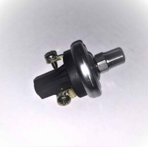 Close-up of a mechanical part with a metal threaded end, black plastic body, and two screws securing brass terminals, photographed on a white background.